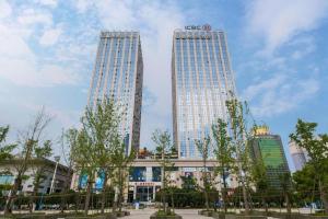 three tall buildings in a city with trees in front at Fortune International Hotel in Xingyin Wanfenglin Airport