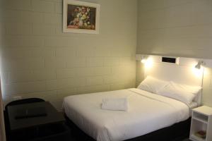 a bedroom with a white bed with a picture on the wall at Central Coast Motel in Wyong