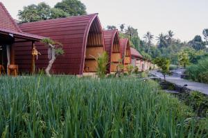 un edificio con tetti rossi e un campo di erba alta di Uma Raos Cottage ad Ubud