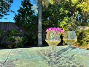 two wine glasses and a vase of flowers on a table at Little Oasis - Palm Room in Port Elizabeth +11 photos