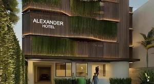 Un bâtiment avec une femme debout devant lui dans l'établissement Alexander Hotel Tegal, à Tegal