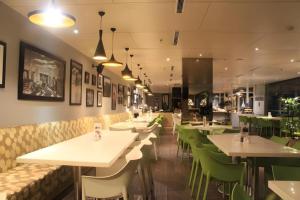 a restaurant with white tables and green chairs at Pomelotel Patra Kuningan Jakarta in Jakarta
