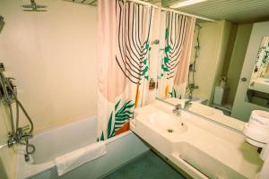 a bathroom with a sink and a tub and a mirror at Kulturhotel Hessenland Kassel Innenstadt by stay awesome in Kassel