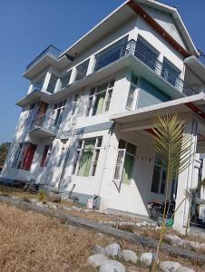 a white house with a palm tree in front of it at Star Amaya Homestay River Side Mountain and Forest View in Kangra Airport