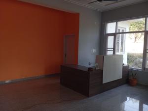 an empty room with orange walls and a large window at Star Amaya Homestay River Side Mountain and Forest View in Kangra Airport