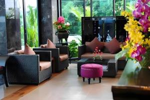 a living room with couches and a table and flowers at Bonito Chinos Hotel in Nakhon Sawan
