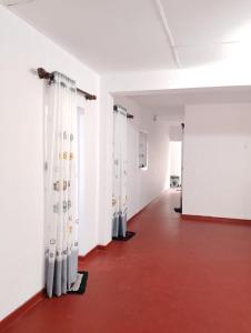 Un pasillo con cortinas blancas y suelo rojo. en Villa Aavanthana, en Ambalangoda