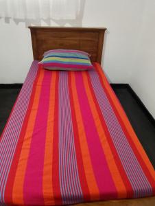 Una cama con un edredón de rayas de colores y una almohada. en Villa Aavanthana, en Ambalangoda