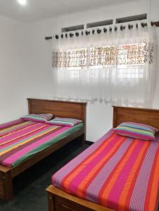 Dos camas una al lado de la otra en una habitación. en Villa Aavanthana, en Ambalangoda
