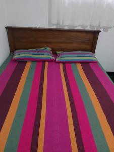 Una cama con una colcha de rayas de colores y dos almohadas. en Villa Aavanthana, en Ambalangoda 1 foto más