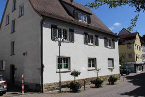 a white building with black shutters on a street at Bismarck Hostel Öhringen in Öhringen