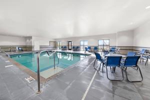 a swimming pool with chairs and a table in a building at Comfort Inn & Suites West - Medical Center in Rochester