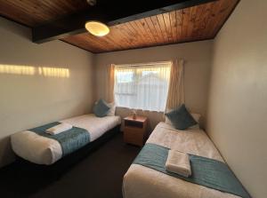 two beds in a room with a window at Mountain View Motel in Taupo