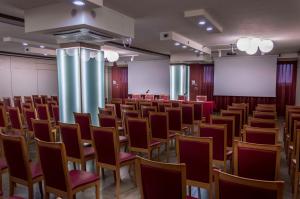 an empty lecture hall with red chairs and a screen at Hotel La Bussola in Novara