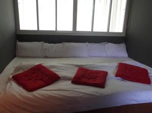 a large white bed with two red pillows on it at Marina Residence in Bang Rak Beach