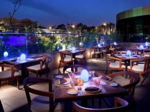 ein Restaurant mit Tischen und Stühlen auf einer Terrasse in der Nacht in der Unterkunft voco - Riyadh, an IHG Hotel in Riad