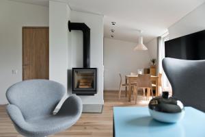 ein Wohnzimmer mit 2 Stühlen und einem Kamin in der Unterkunft Aura apartamentai in Druskininkai