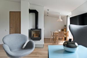 a living room with two chairs and a fireplace at Aura apartamentai in Druskininkai