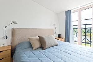 a bedroom with a blue bed with a window at Aura apartamentai in Druskininkai