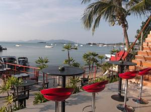 a patio with tables and chairs next to the water at Marina Residence in Bang Rak Beach
