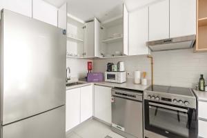 a kitchen with white cabinets and a stainless steel refrigerator at Silkhaus 1BDR Serene Stay in Reem Island in Mushayrib