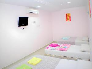 Una habitación con dos camas y un televisor en la pared. en Taipann Hotel, en Kampong Telok Gadong Besar