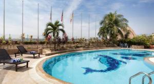 a large swimming pool in a resort with palm trees at Summit Hotel Subang USJ in Subang Jaya