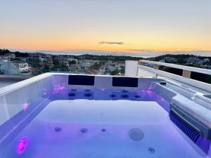 a hot tub on top of a balcony with the sunset at Villasonboard 3 Bed Penthouse Veranda Beach view jacuzzi Vouliagmeni Riviera in Athens