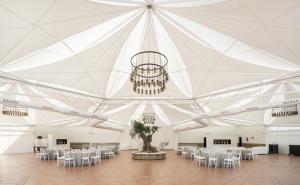 a large white tent with tables and chairs and a chandelier at Hotel Ilunion Las Lomas in Merida +25 photos