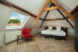 een slaapkamer op zolder met 2 bedden en een rode stoel bij Stayci Serviced Apartments Denneweg in Den Haag