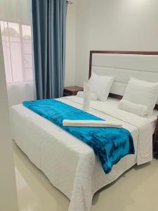ein großes weißes Bett mit einer blauen Decke drauf in der Unterkunft Poinsettia White House in Livingstone