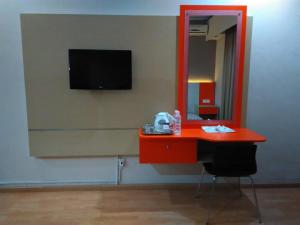 a red desk with a mirror and a tv on a wall at Hotel Taufina Solok in Solok
