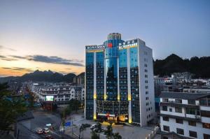ein hohes Gebäude mit Lichtern in einer Stadt in der Unterkunft Borrman Hotel Hechi Bama Central Cultural Plaza in Bama