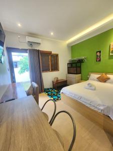 a bedroom with a bed and a table and a green wall at Nana's Villa Sanur in Sanur