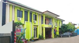 un bâtiment jaune avec un homme debout à l'extérieur dans l'établissement SPOT ON 2815 Hotel Damai, à Cilacap