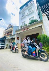 two people riding on a motorcycle in front of a building at Lantana Homestay in Da Lat