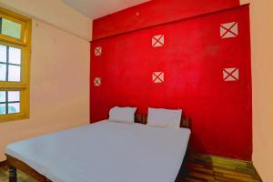 1 dormitorio con pared roja y cama blanca en HOTEL O SK GRAND, en Sitāpur
