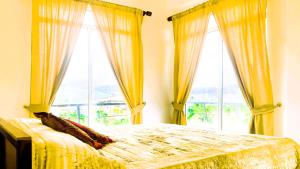 a bedroom with a bed with yellow curtains and windows at Lotus View Home in Nuwara Eliya