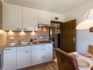 une cuisine avec des armoires blanches et une table dans l'établissement Zahmer Kaiser, à Oberaudorf 3 autres photos