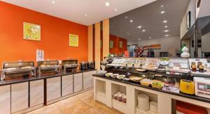 a restaurant with orange walls and a counter with food at 7 Days Premium Zibo Jinjing Avenue the Mixc in Zibo