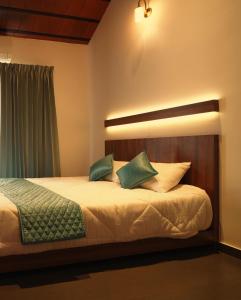 维特利Punarjeevani Ayurvedic Heritage的卧室里有一张床，上面有绿色和白色的枕头