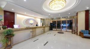 a lobby of a hotel with a man standing at a counter at GreenTree Inn JinDeZhen People Square Taoxichuan Wenchuang Street in Jingdezhen