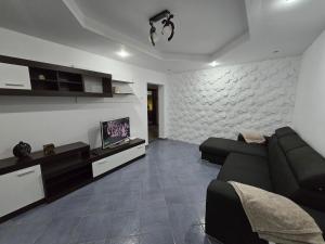 a living room with a black couch and a tv at AARON Apartament in Craiova