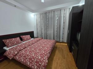 a bedroom with a bed with a red comforter and a television at AARON Apartament in Craiova