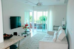 uma sala de estar com um sofá branco e uma televisão em Camboinhas Oceanside Oceanfront no Rio de Janeiro