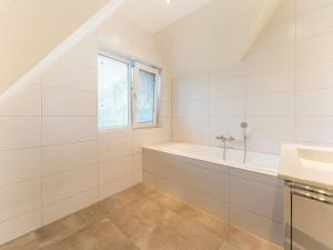 une salle de bain blanche avec une baignoire et une fenêtre dans l'établissement Serene Holiday Home in De Koog Texel with Sauna, à Westermient 24 autres photos