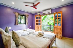 two beds in a room with purple walls at Hotel Eyokar Goa in Candolim +54 photos