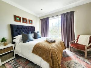 Un dormitorio con una cama y una silla y una ventana. en Modern Coastal Apartment in J-Bay, en Jeffreys Bay