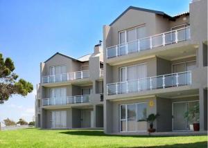 Un edificio de apartamentos con césped delante. en Modern Coastal Apartment in J-Bay, en Jeffreys Bay