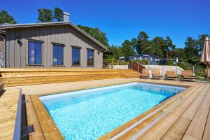 ein Swimmingpool mit Holzterrasse und ein Haus in der Unterkunft Daftö Resort in Strömstad